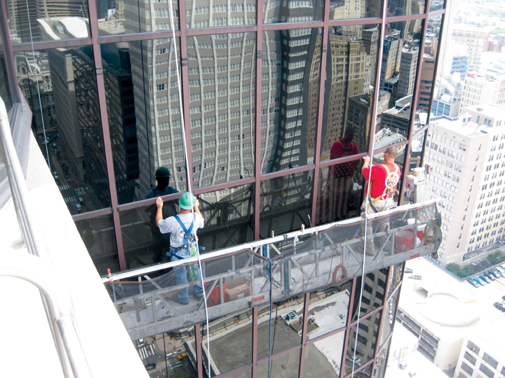 Workers repair a failed glass curtain wall. As glazed curtain walls age, many o