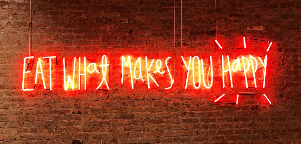 Neon sign with 'Eat what makes you happy' written