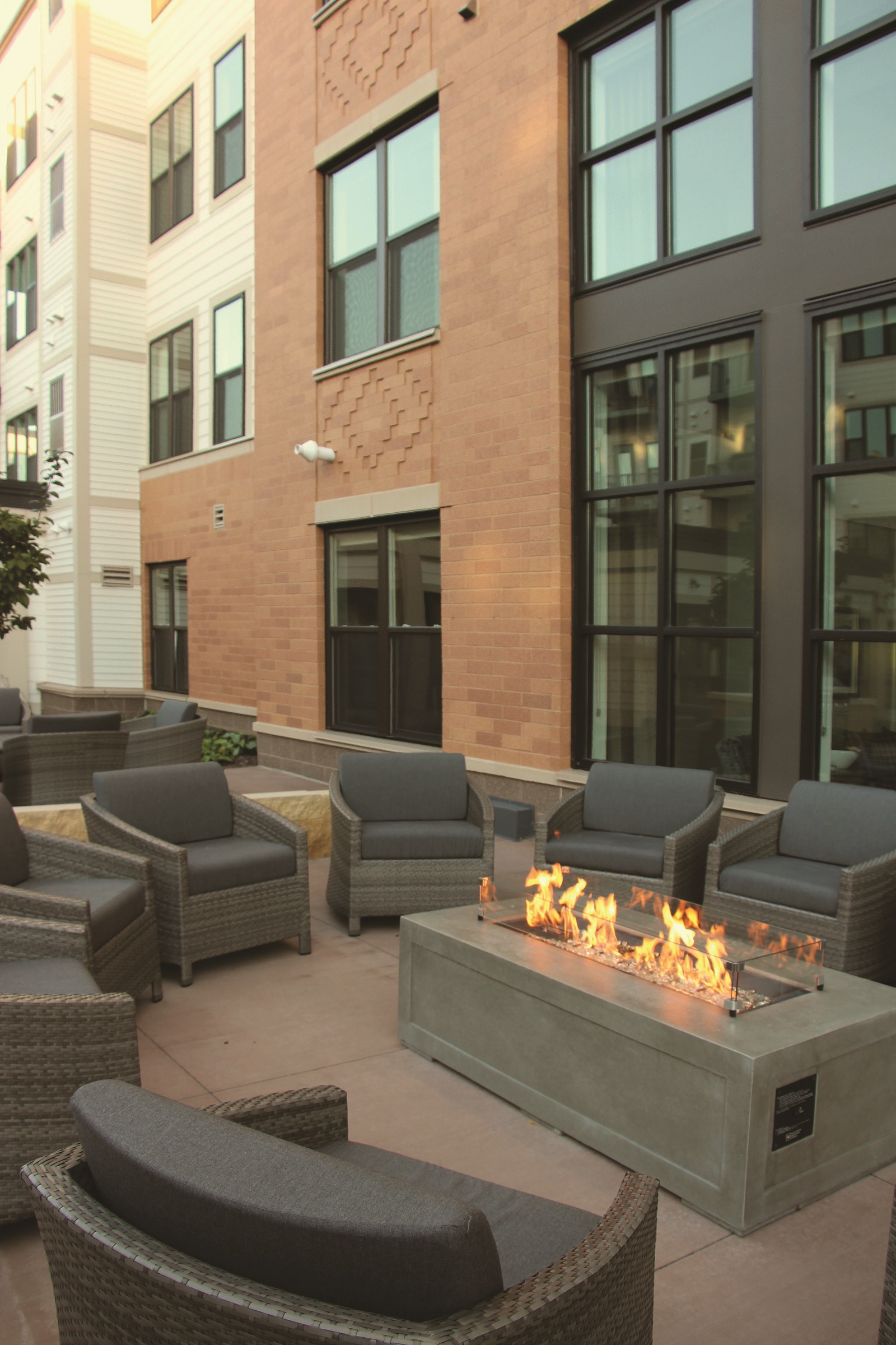 A modern apartment exterior with comfortable seating around a fire pitand no visible HVAC units to get in the way