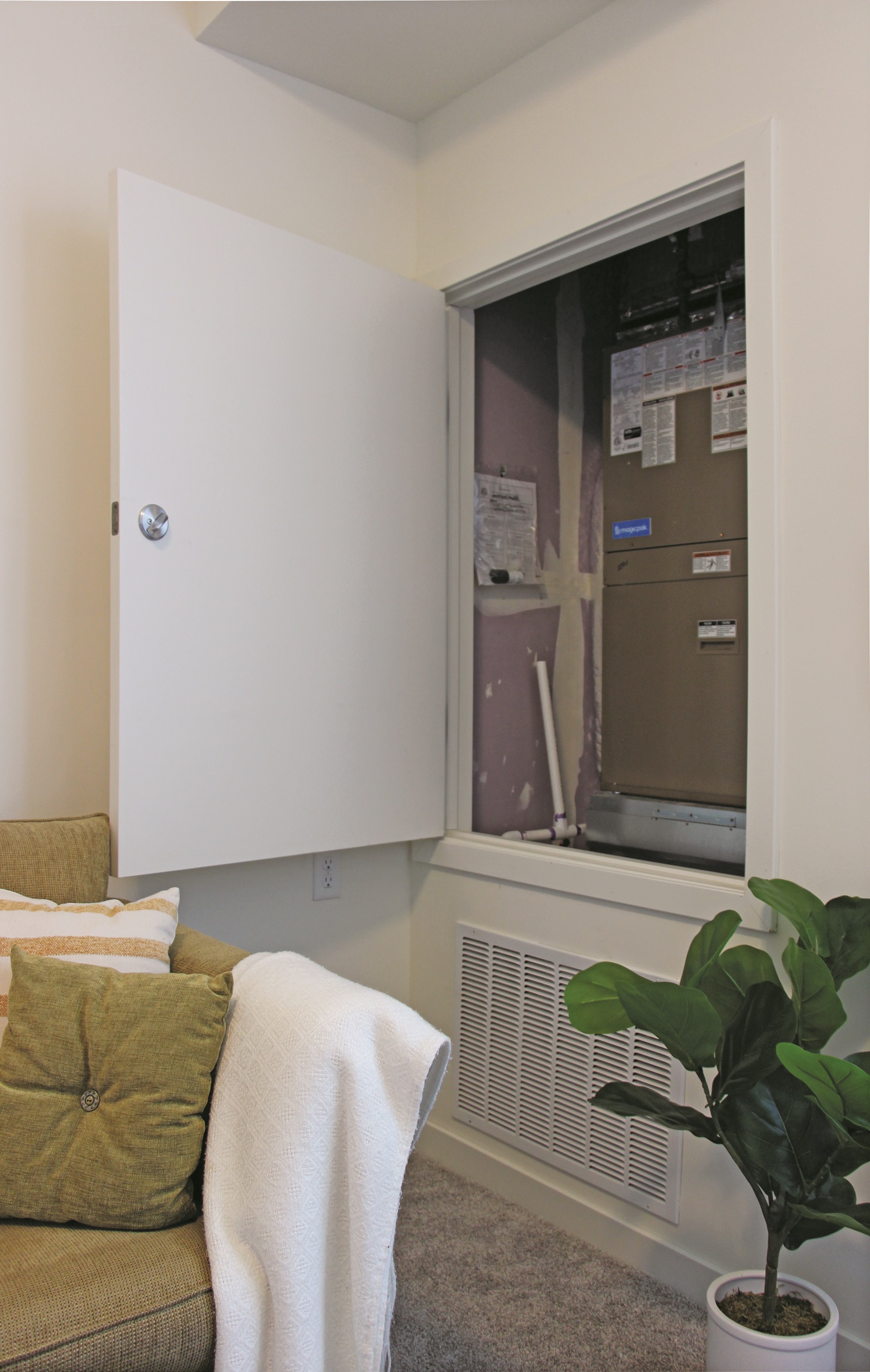 Apanel in the wall of an apartment opens for maintenance access to the MagicPak HVAC unit