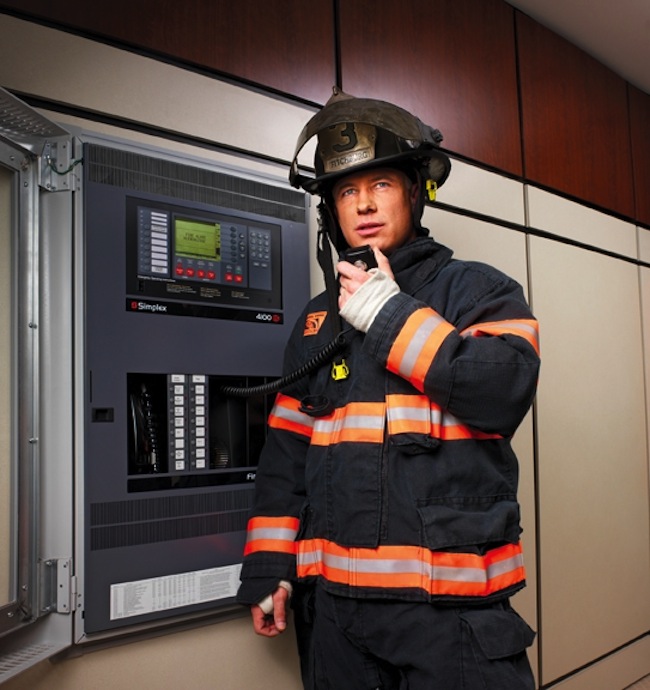 A firefighter uses the voice capabilities of a fire alarm panel (in this case, a