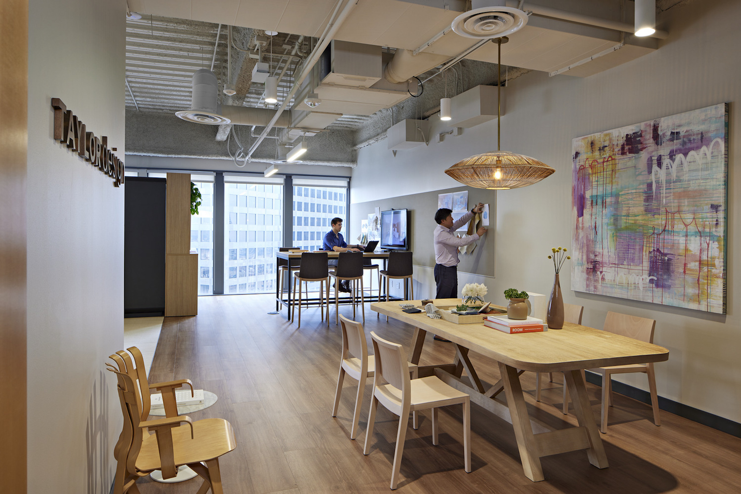 This photo of Taylor Design’s LA office shows standard branding, decorative lighting, and a family table (the 70%), with community art (the 30%) unique to the location.