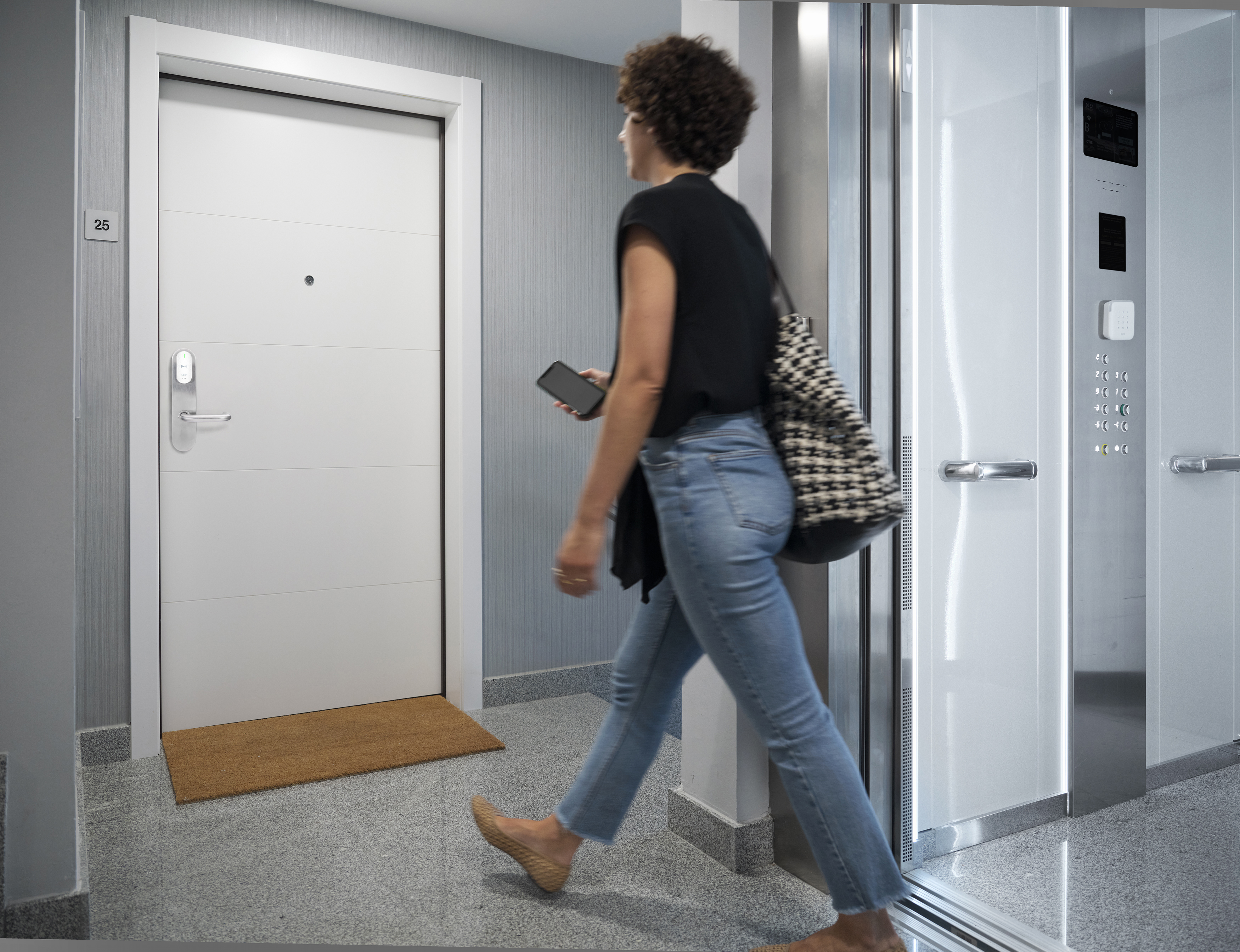 A woman uses her iPhone to access the elevator and her apartment door.