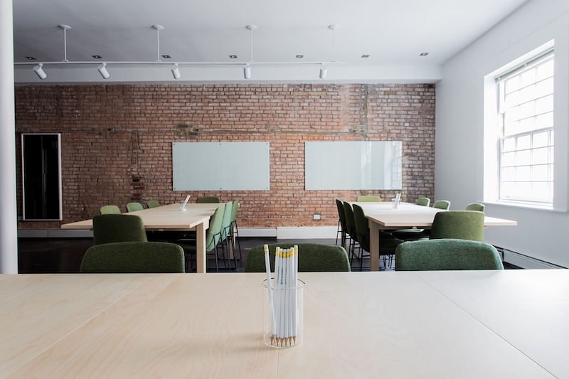 A classroom with large tables and a brick wall