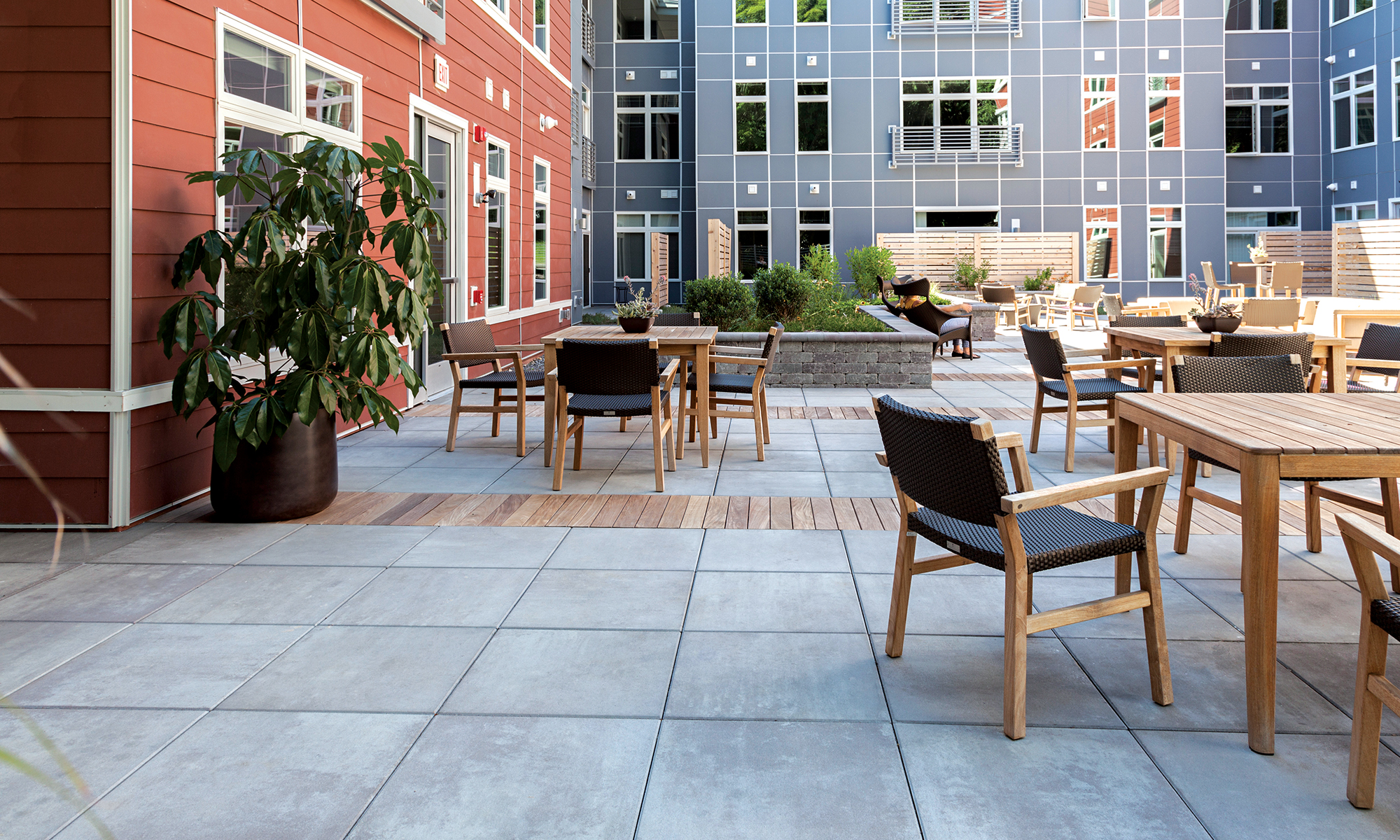 At 99 Tremont, a multifamily development in Brighton, Massachusetts, concrete slabs interspersed with wooden plank accents create an aesthetic surface on an elevated courtyard.