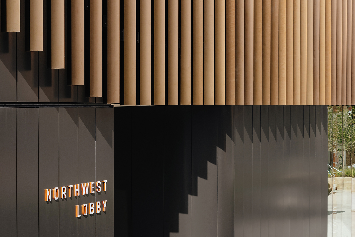 Warm wood tones and crisp MCM paneling ebb and flow in the interior and exterior of Moody Center