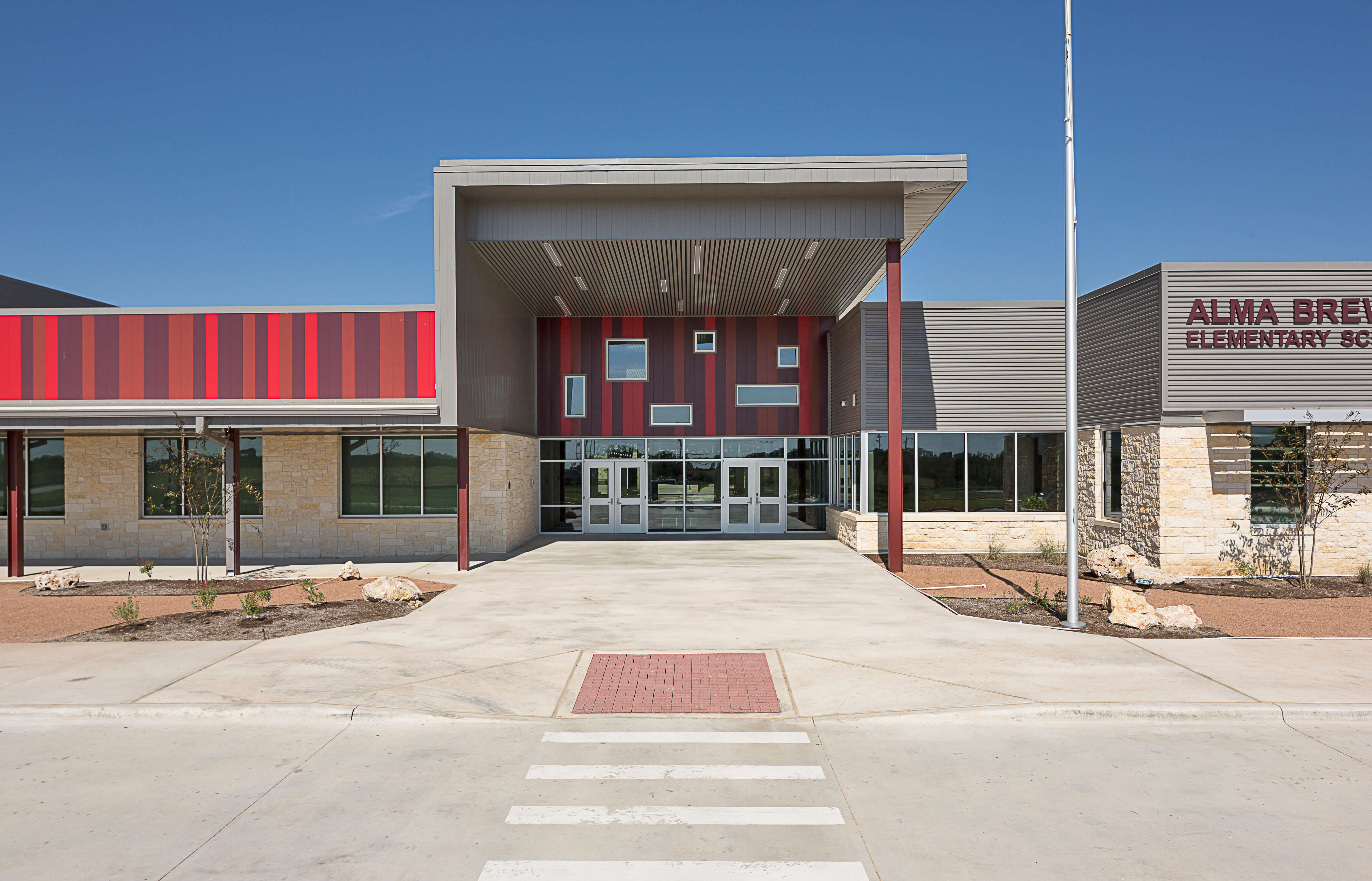 Flush metal wall panels in three shades of red in a seemingly random pattern add a playful feel to the Alma Brewer Strawn Elementary School in Lytton Springs, Texas. Photo: buenavistaphotography.com