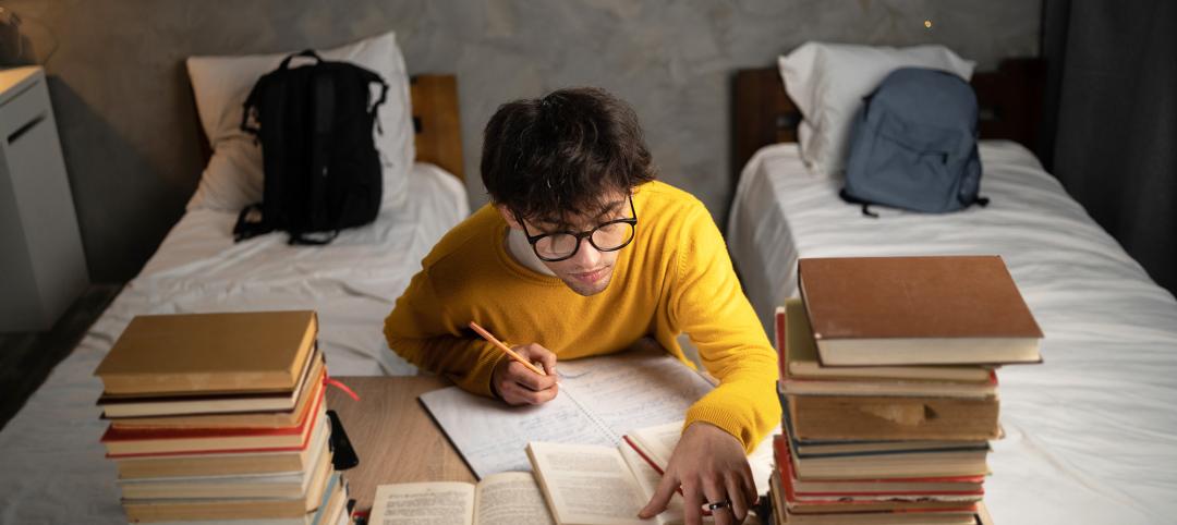 Serious male student writing, reading books and prepare for college exam in dormitory room. Top view.
