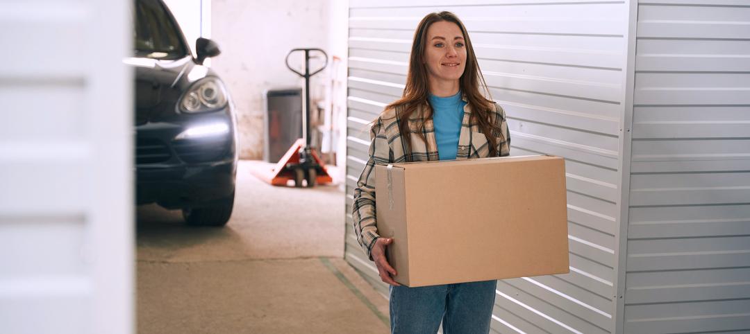 Young lady with big cardboard boxes into warehouse with self-storage unit