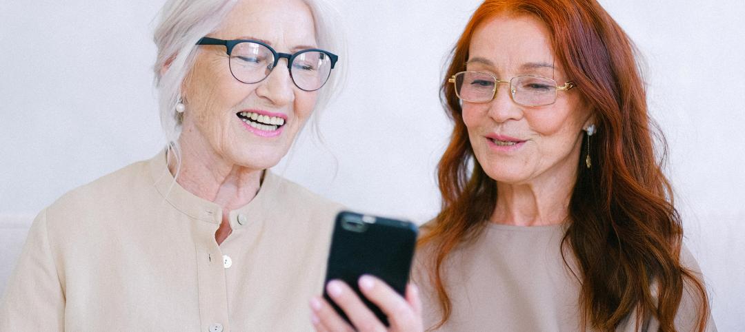 Happy senior women in eyeglasses looking at screen of smartphone