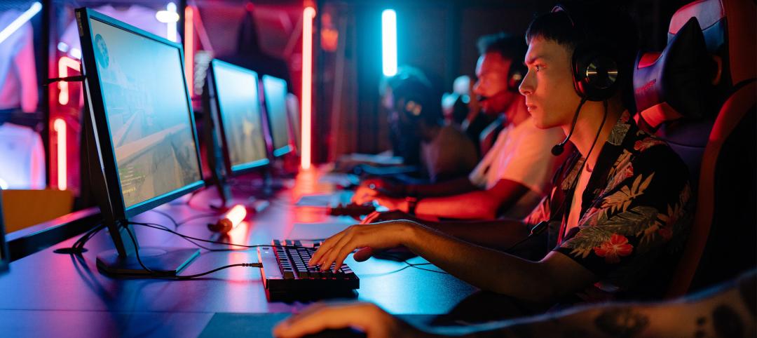 Esports gamers playing at long desk in dark room