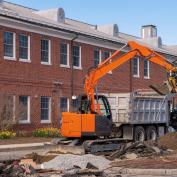 Excavator digging a trench and loading on the dump truck in Middlesex Community College in town of Bedford, Massachusetts MA, USA