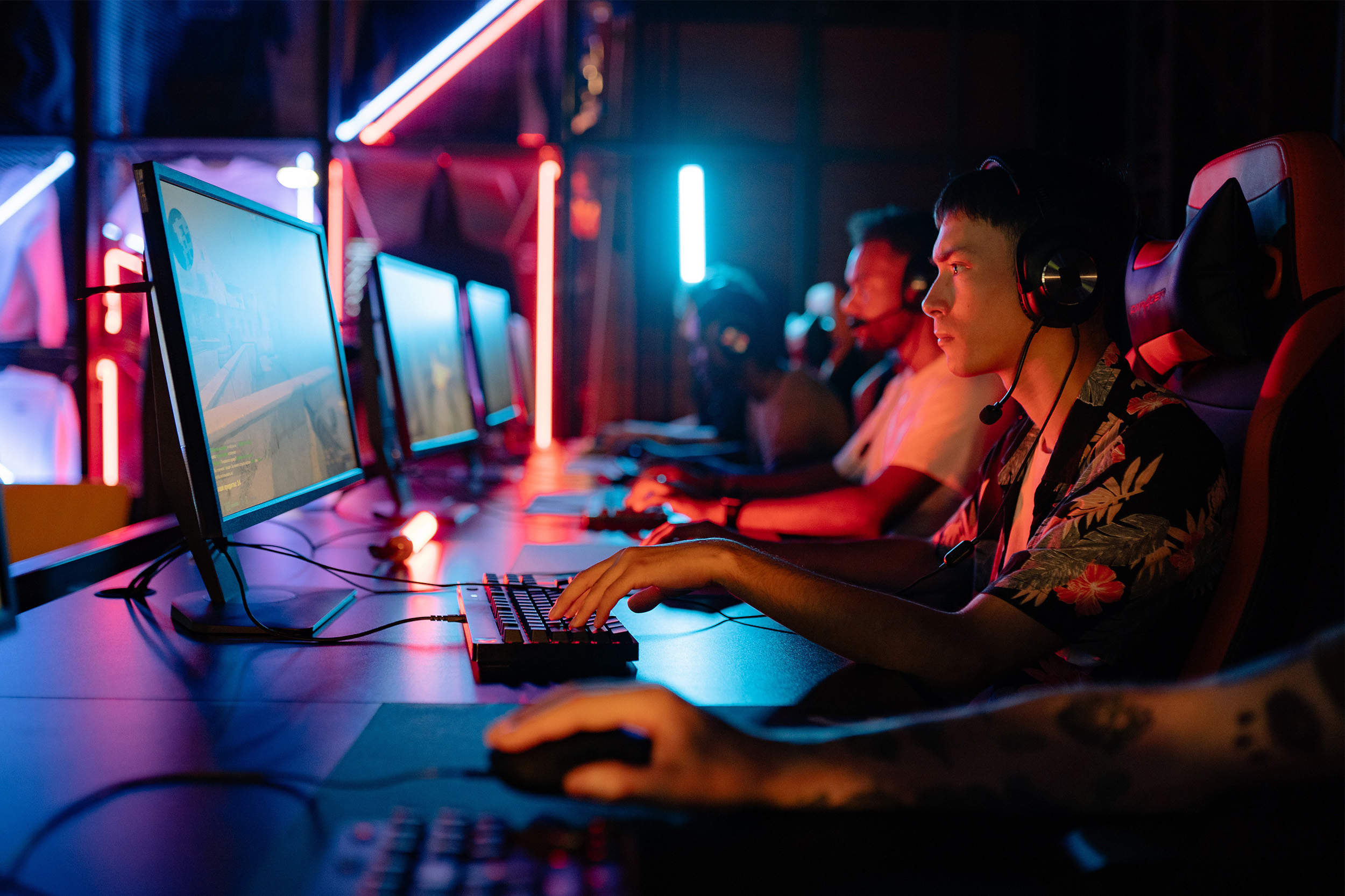 Esports gamers playing at long desk in dark room